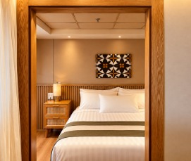 Upper Deck Suite bedroom with wooden doorway and woven cane nightstand aboard Q-Nile