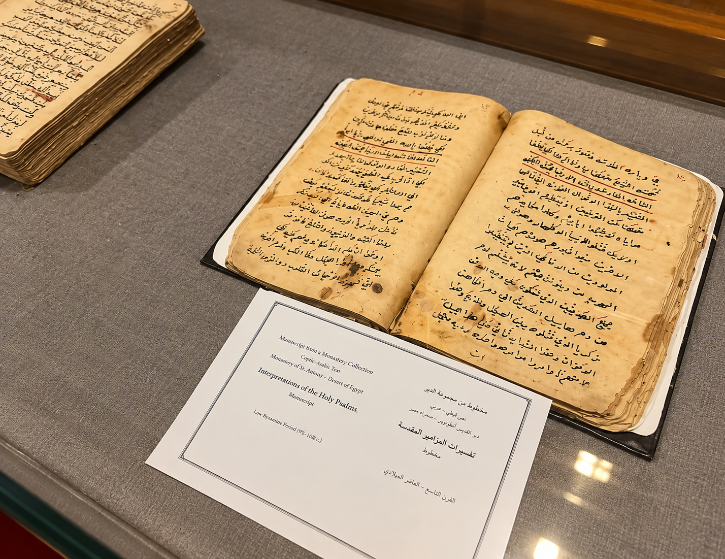 A monastery manuscript open in a display case beside its explanatory label
