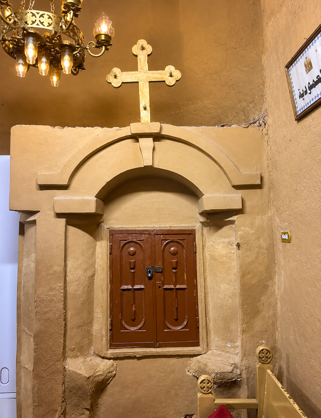 Warm candlelit chapel niche with carved wooden doors inside the monastery