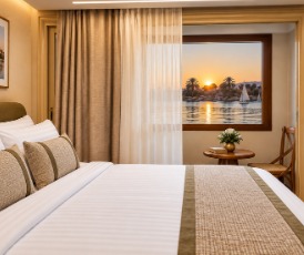 Queen bed with a private veranda view over the Nile at sunset aboard Q-Nile
